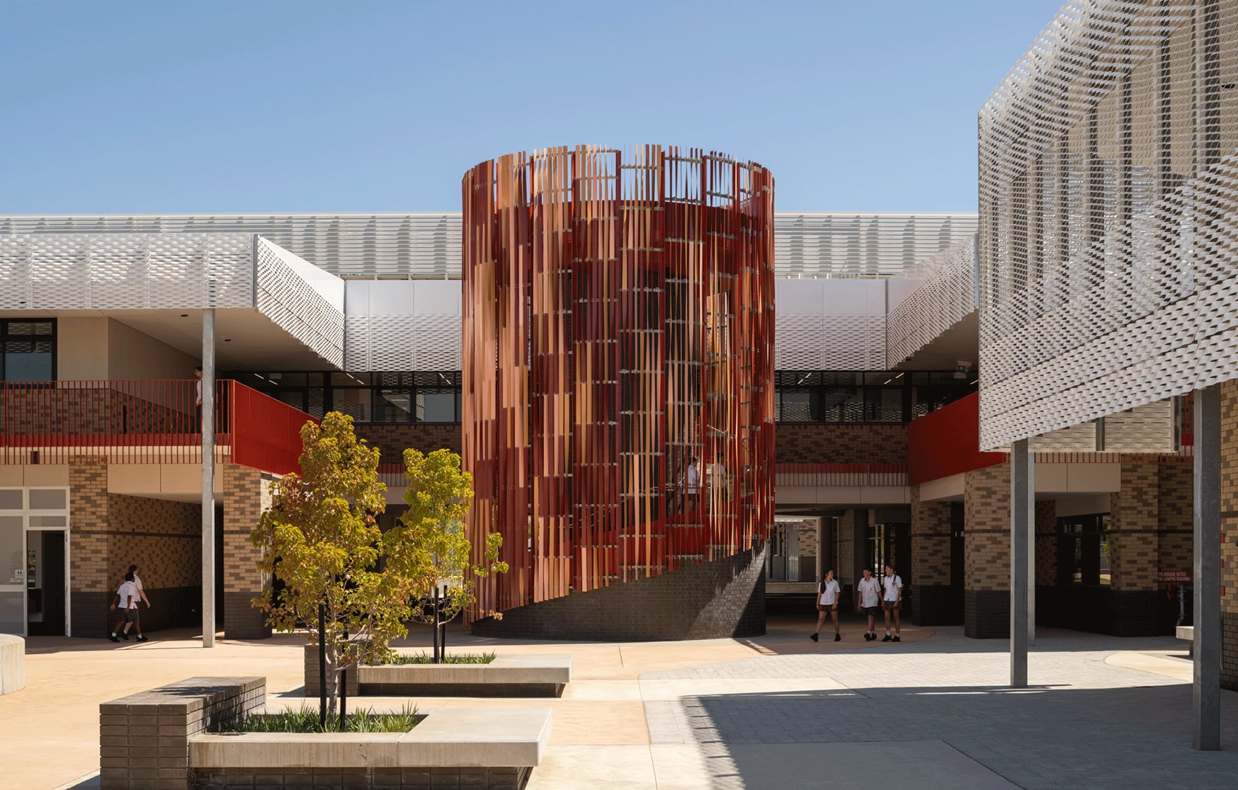 Students cross the courtyard past Anthesis, its banksia coloured fins spiralling above a dark brick plinth