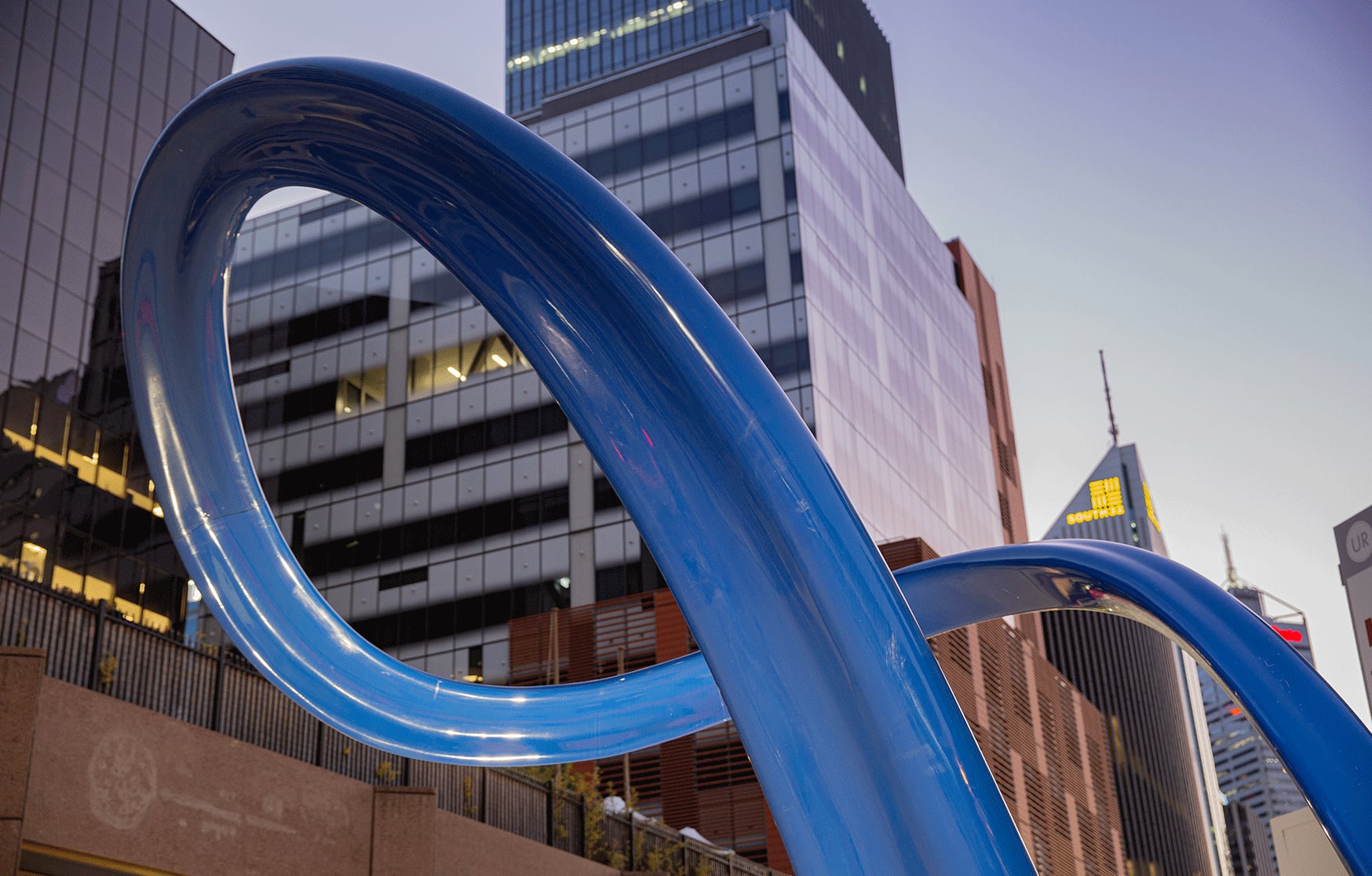 Looking up through Cygna's glossy carbon fibre curves to the towers of East Perth at twilight.