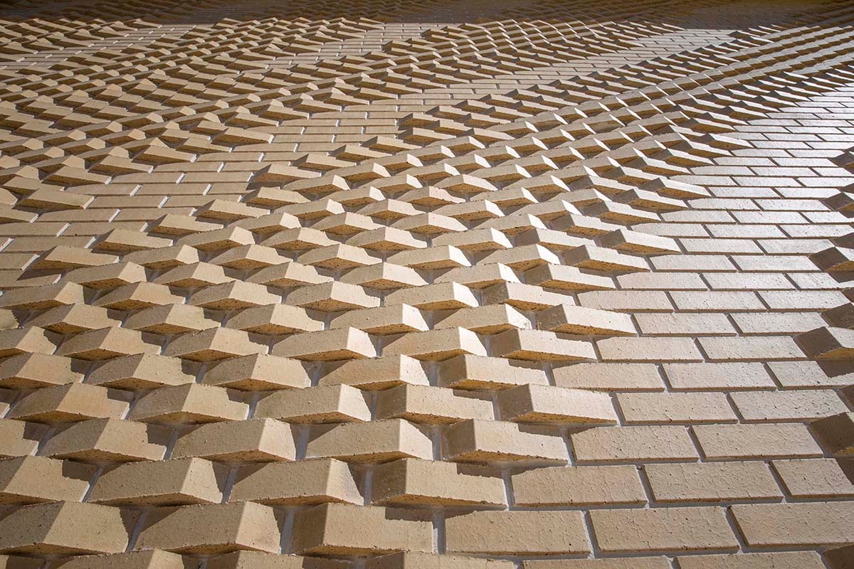 Close-up of custom brick shapes rotated to form dune ripples across the Rhythm and Flow wall at Yanchep.